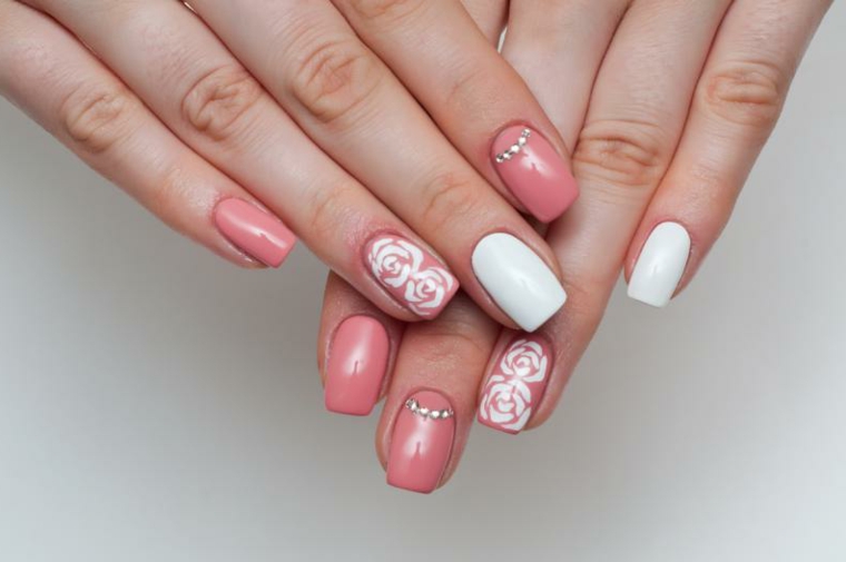 Decorazioni unghie rosa cipria con fiorellini e brillantini, accent nail di colore bianco gel 