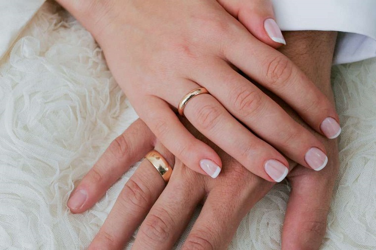 Mani uomo e donna una sopra l'altra, unghie gel semplici ma belle, french bianco su una base rosa chiaro 