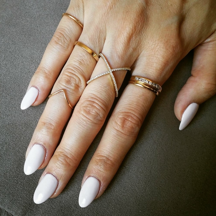 Unghie tonde, smalto color crema per una manicure perfetta in abbinamento agli anelli in oro 