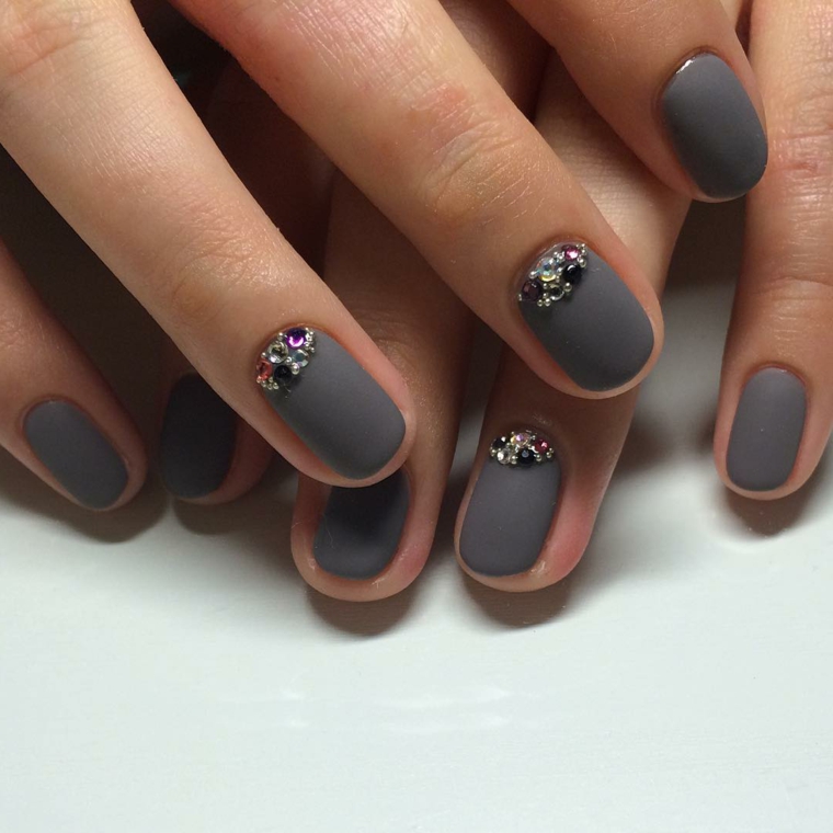 Nail art con brillantini su una base di smalto grigio dall'effetto opaco