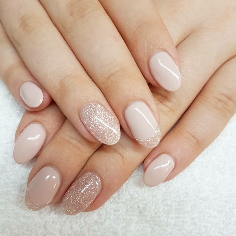 mani dal look naturale con uno smalto nude e anulare decorato con dei glitter